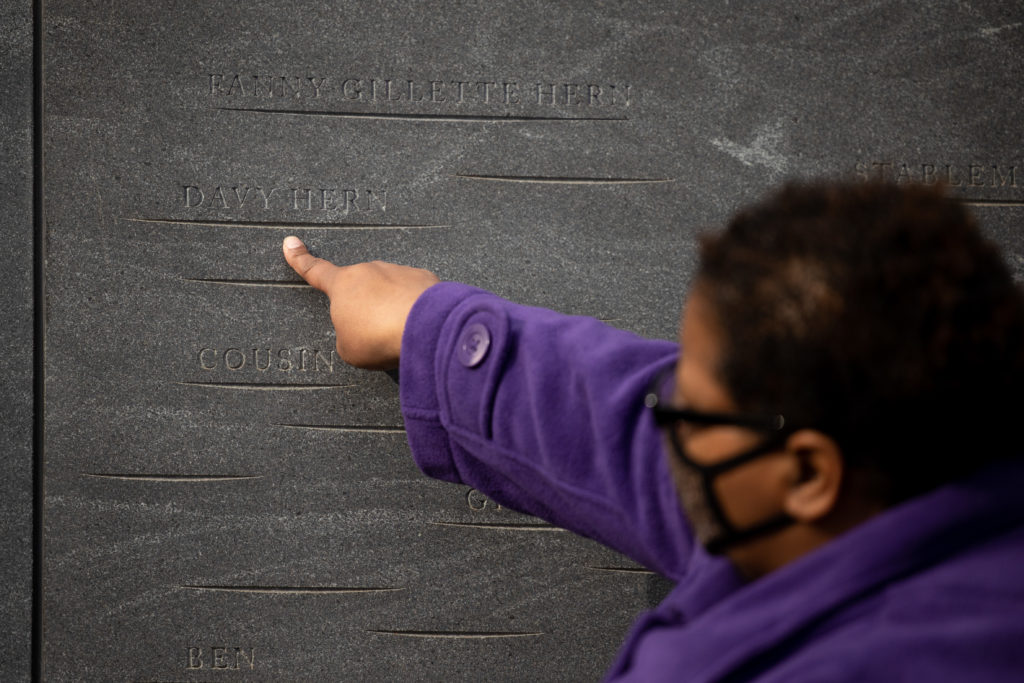 A woman points at an etching on a wall