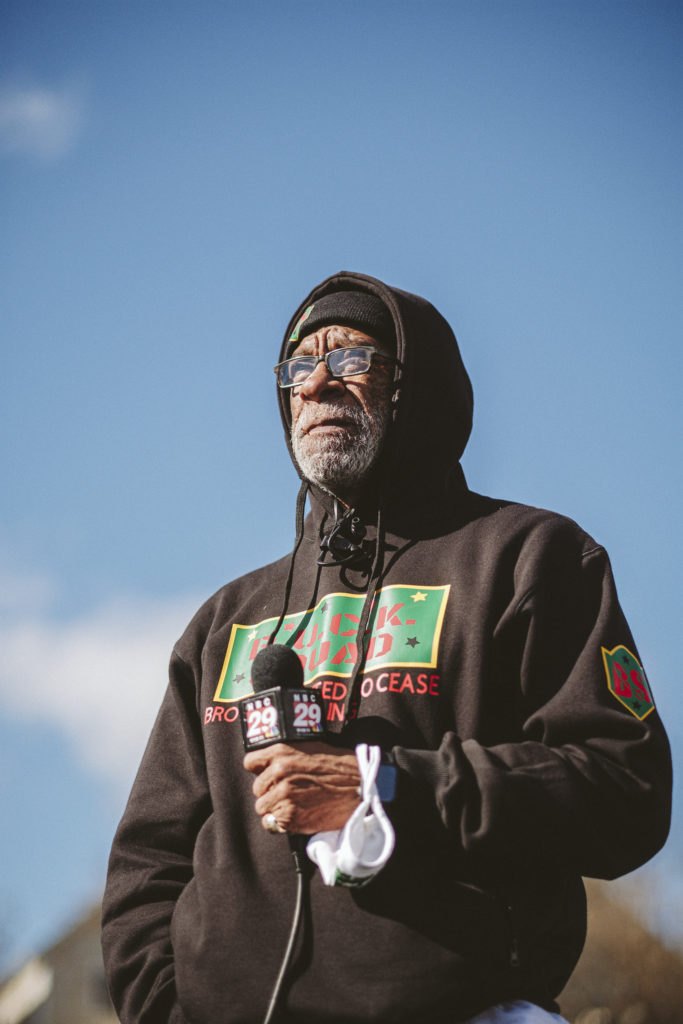 A man in a black sweatshirt holding a microphone is pictured from below.