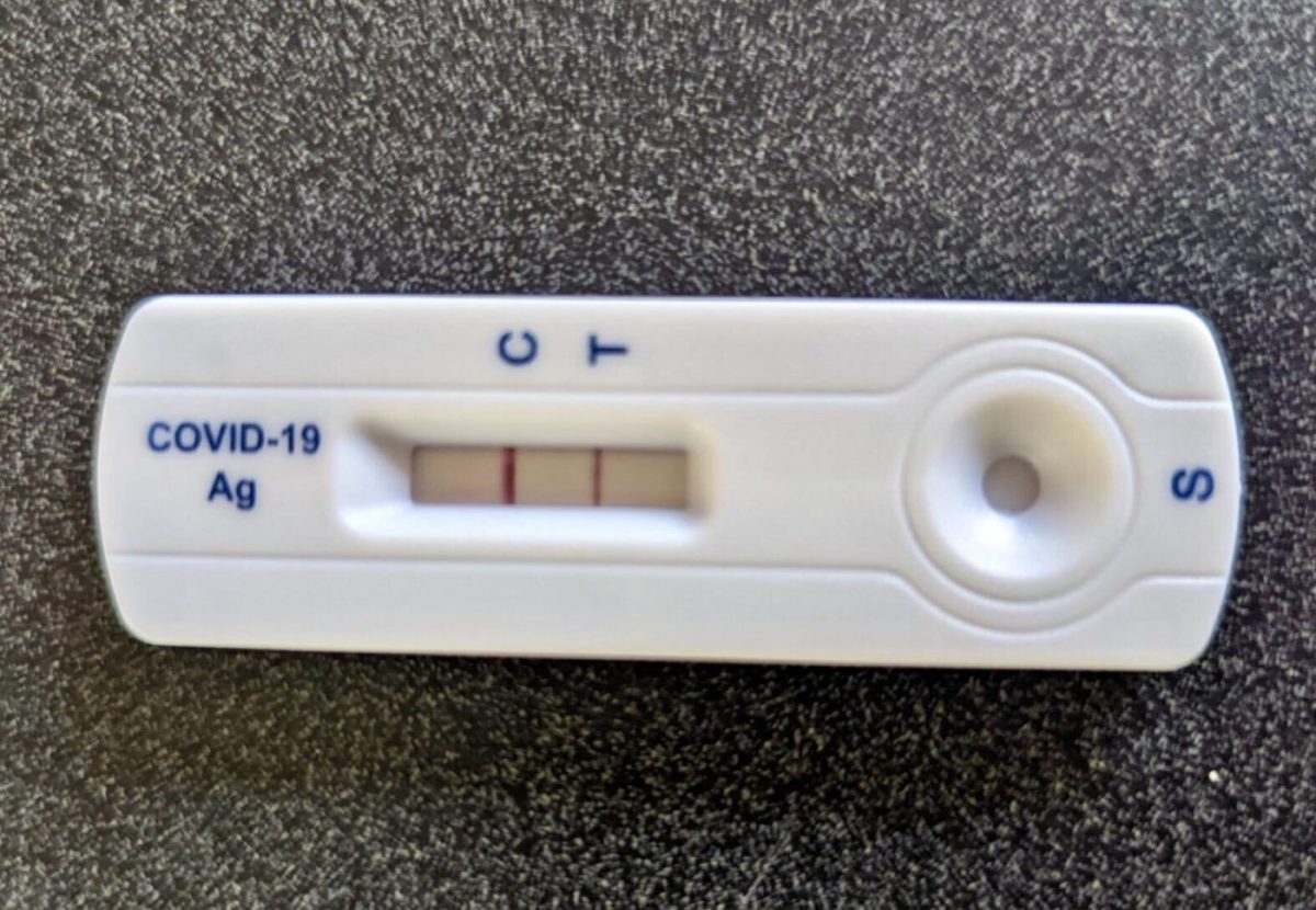 A COVID-19 test shows a positive result, with two pink lines next to the letters “C” and “T.”