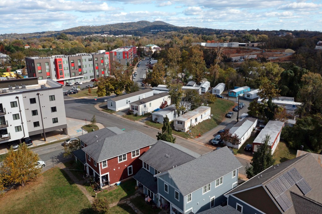 An aerial view of mobile homes surrounded by new homes and apartment buildings.