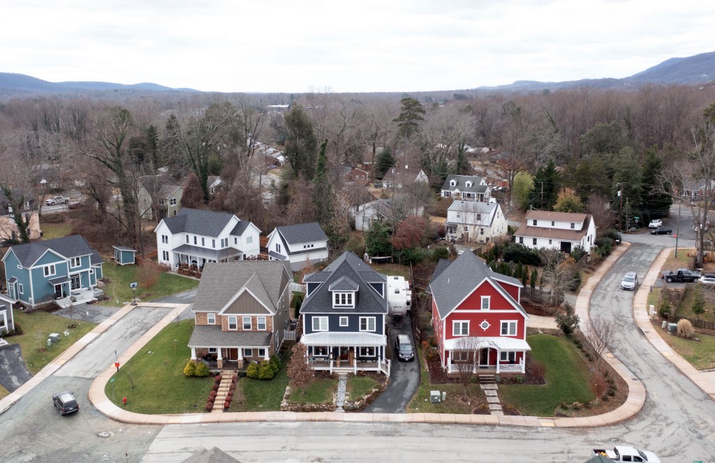 An aerial view of three homes in bright colors on a cul-de-sac, with other homes behind them.
