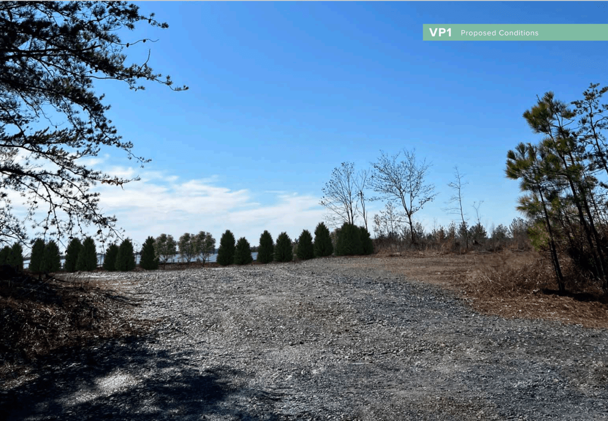 A graveled area is with a few trees in the background and blue sky.