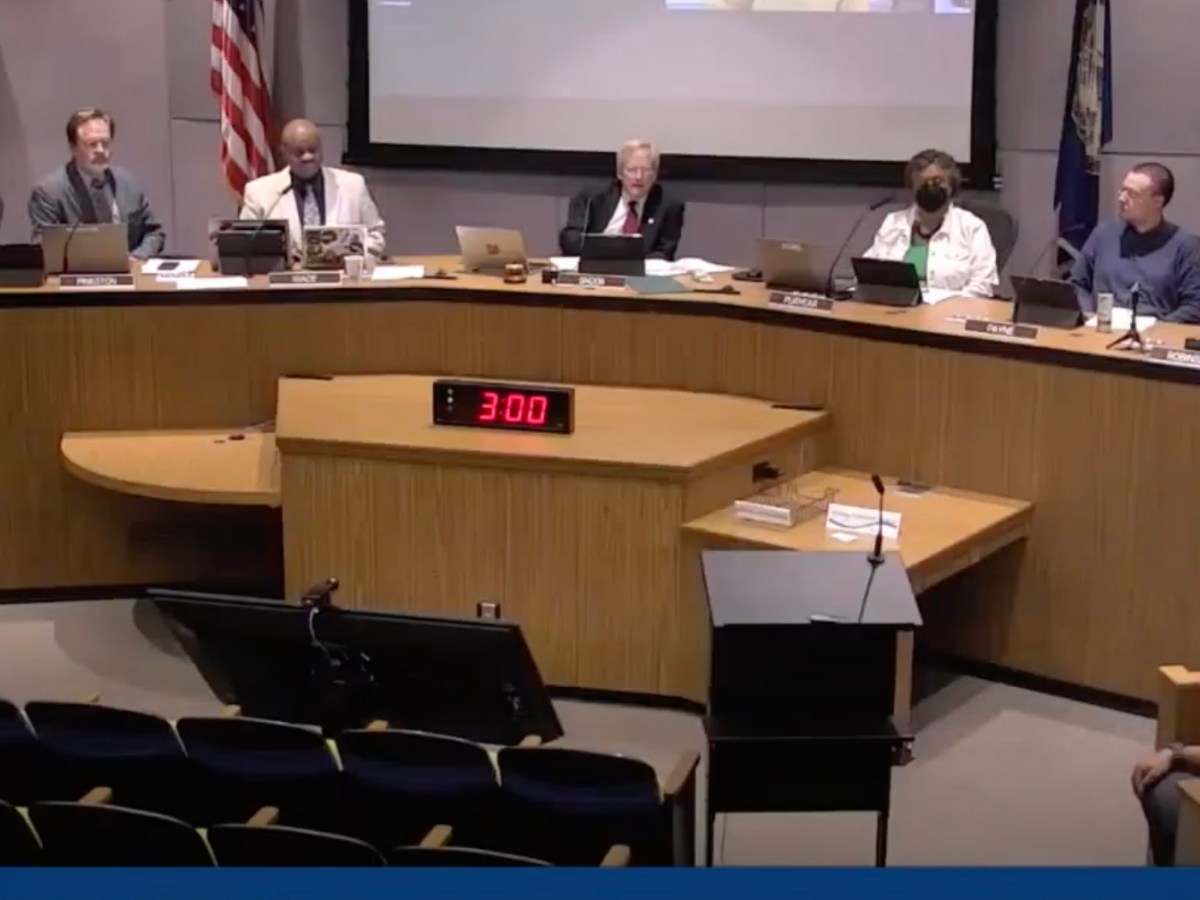 Seven people sit at a dias with a red clock in front of them set to three minutes.