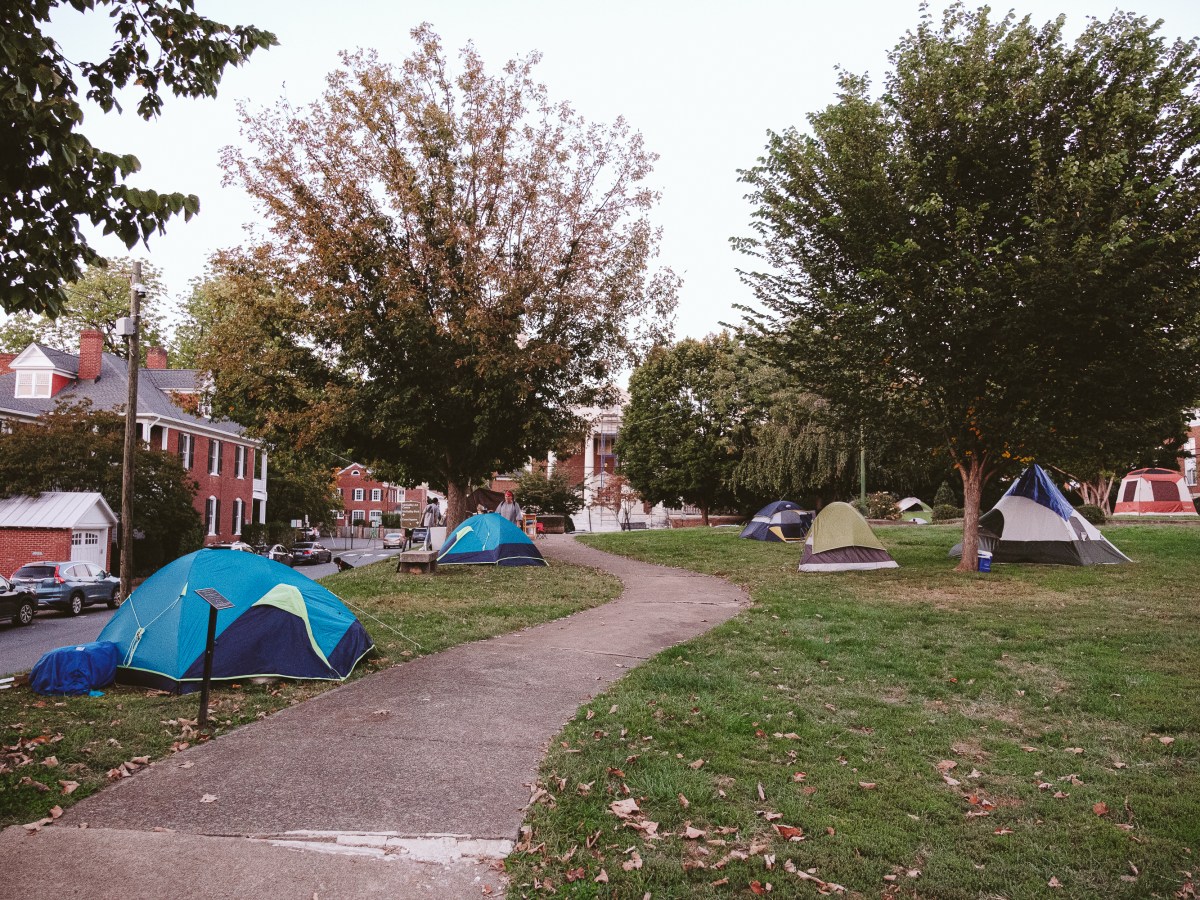 A walkway through a park with trees, colorful tents flanking the sides.