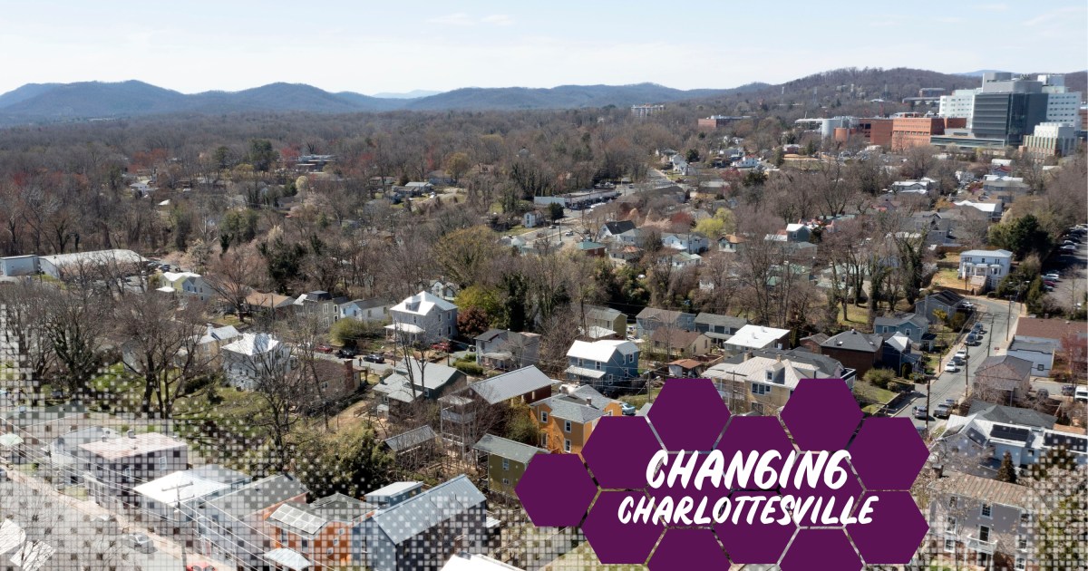 An aerial view of a neighborhood with a large building in the back and mountains in distance.