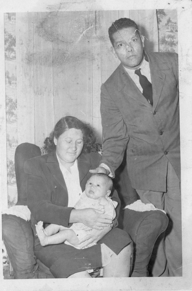 On the right a black and white photo of a woman sitting on a chair with a baby in her lap, and a man in a suit standing next to them, looking at the camera."