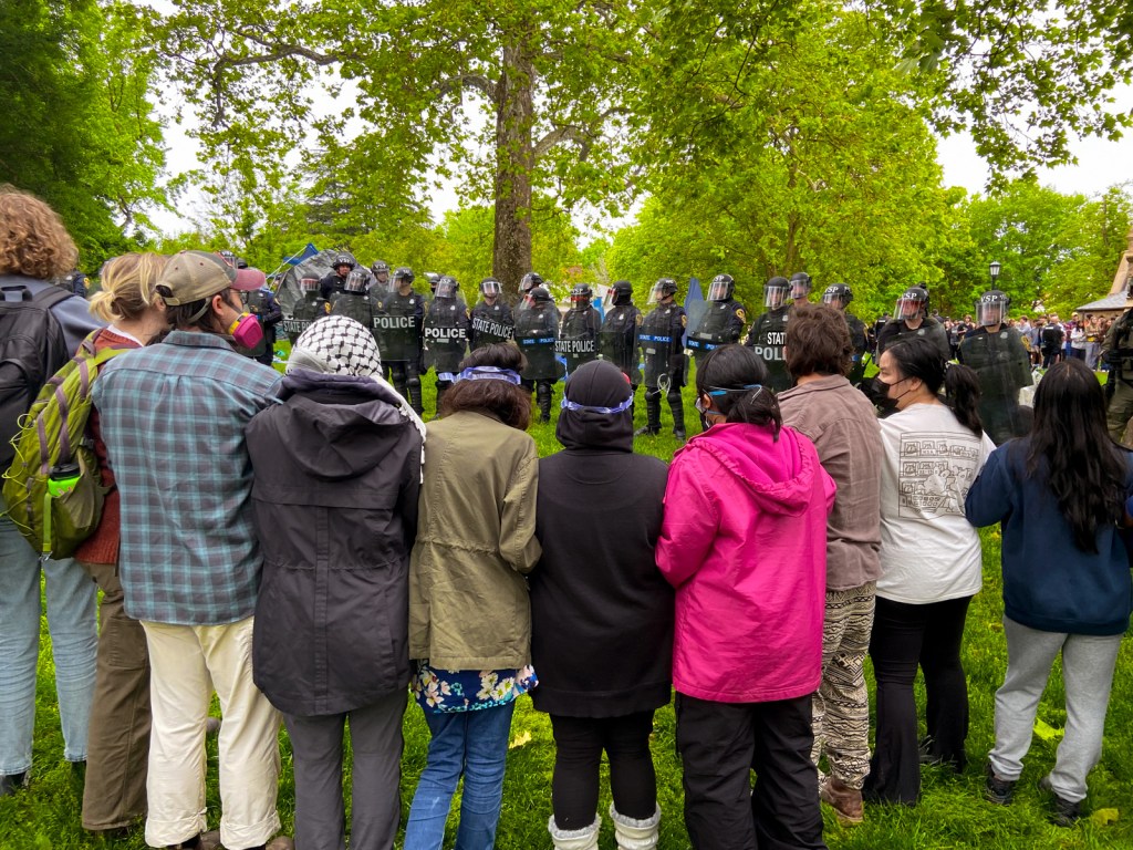 A group of people lined up in front of police in riot gear