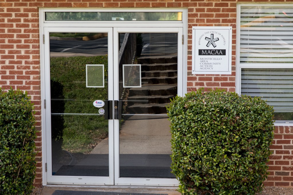 The entrance of a brick building with double glass doors and a sign next to it that reads, "MACAA."