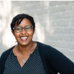 Woman smiling at camera with white bricks behind her
