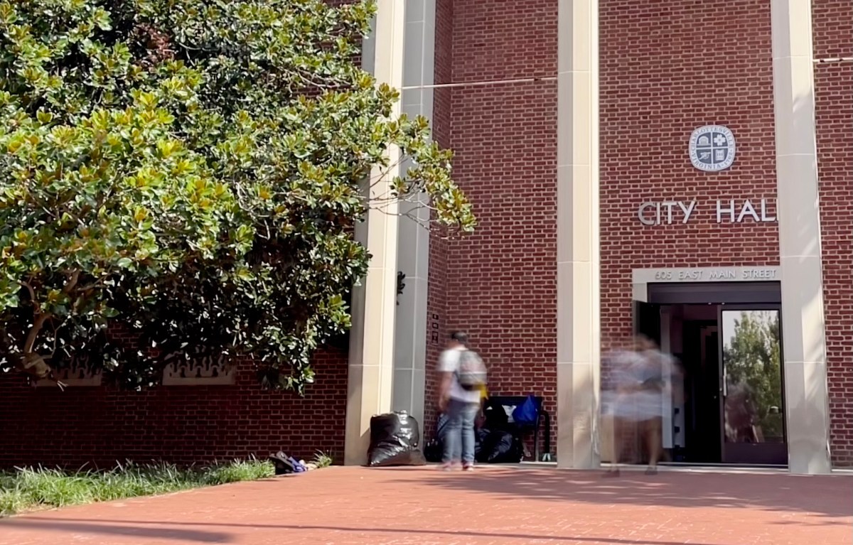 People pictured using motion blur are walking in and out of a brick building with white columns and the words "City Hall" over the door.