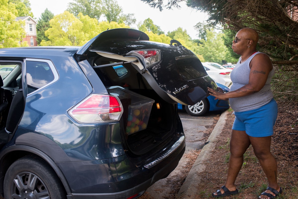 A woman closes the truck of an SUV.