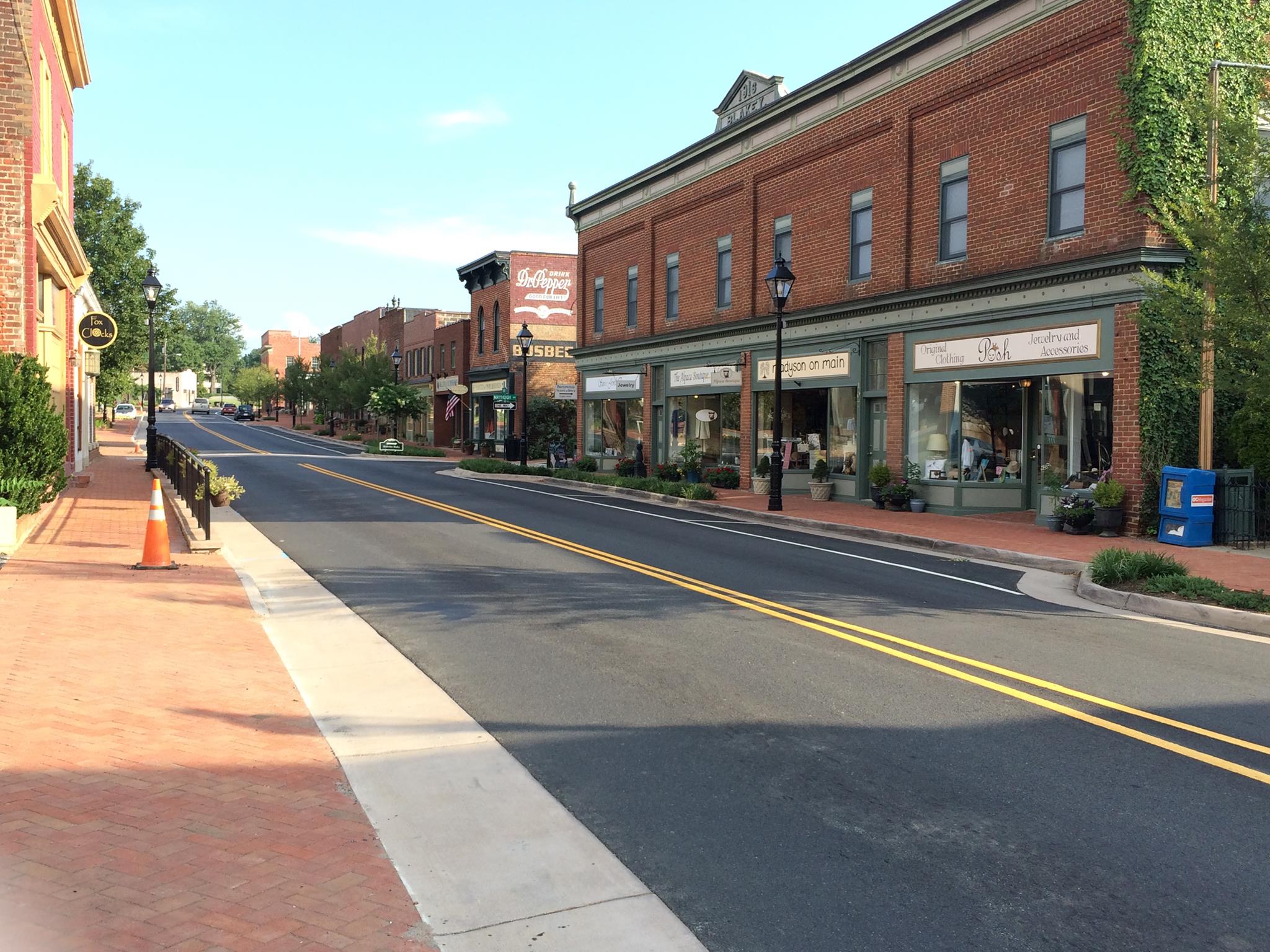 A downtown area of a small town, with a main street, brick sidewalks and brick buildings on either side.