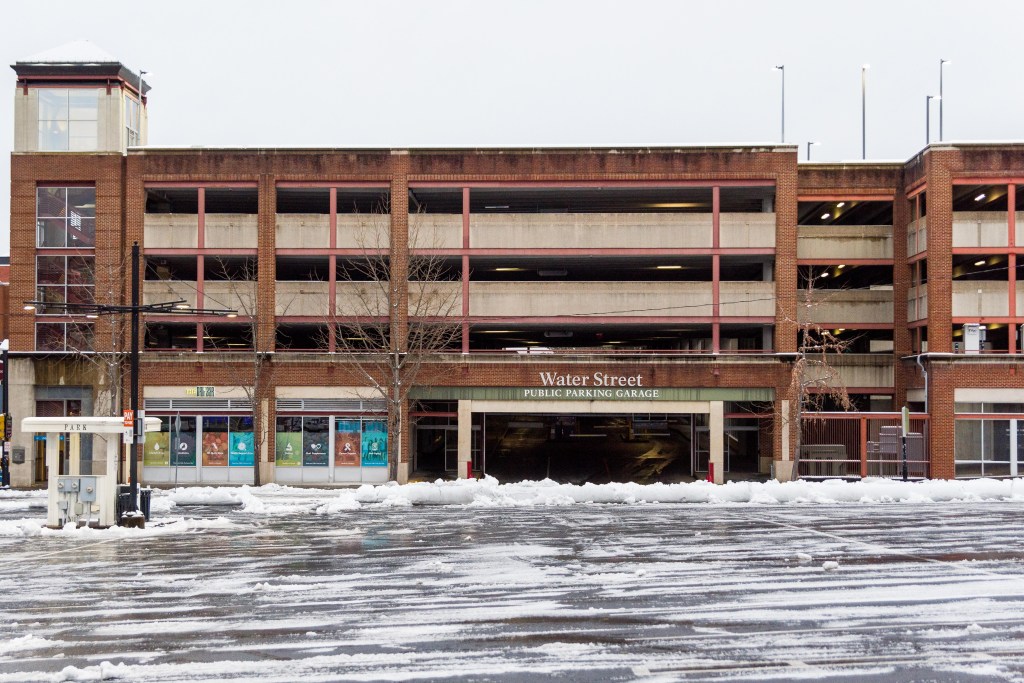An empty street with a four story parking garage, no people or cars.