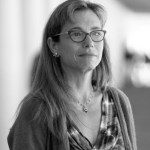 A black and white image of a woman in glasses look off to the side