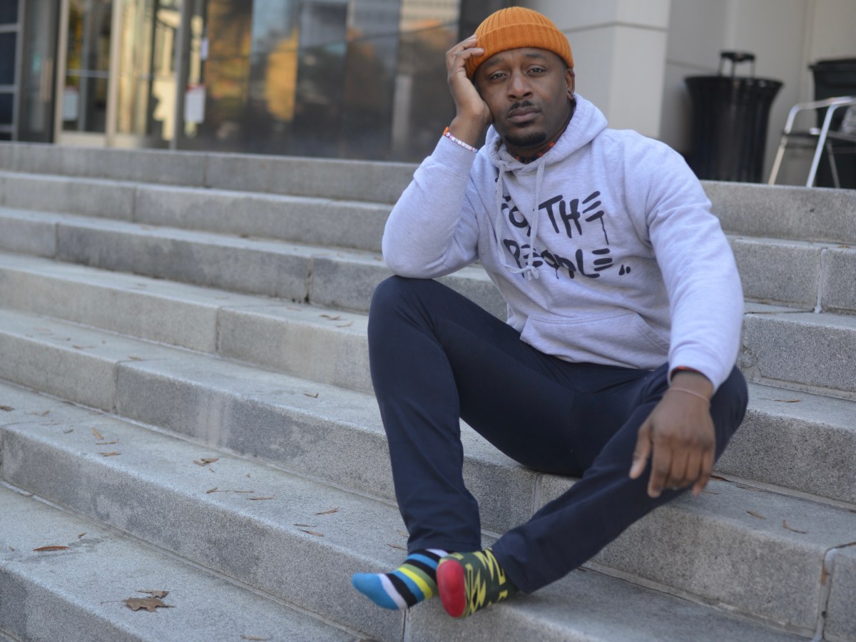 A man sits outside on a flight of stone stairs.