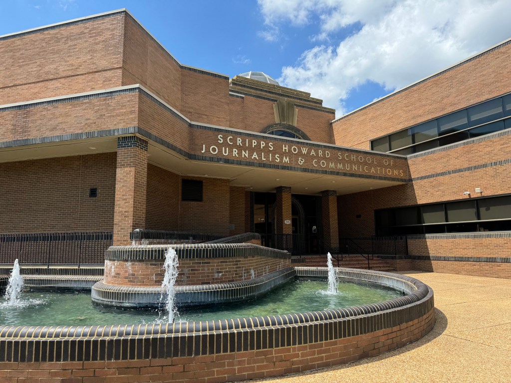 A brick building and courtyard with a tiled fountain. The sign on the building reads, "Scripps Howard School of Journalism & Communication."