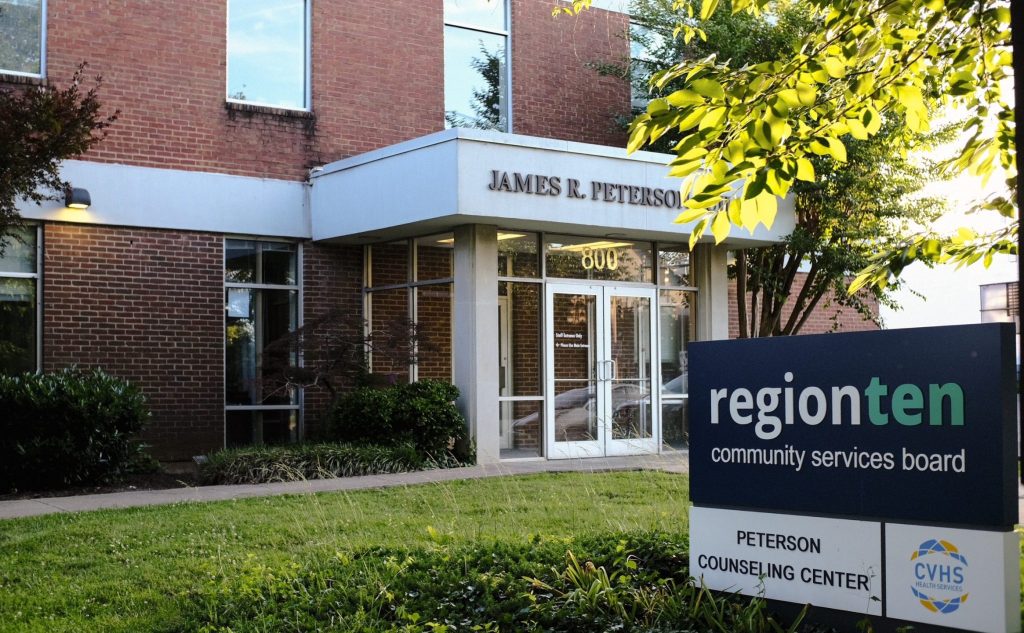 A brick building with large glass doors and grass and trees in front. A large sign in the grass says 'region ten community services board'