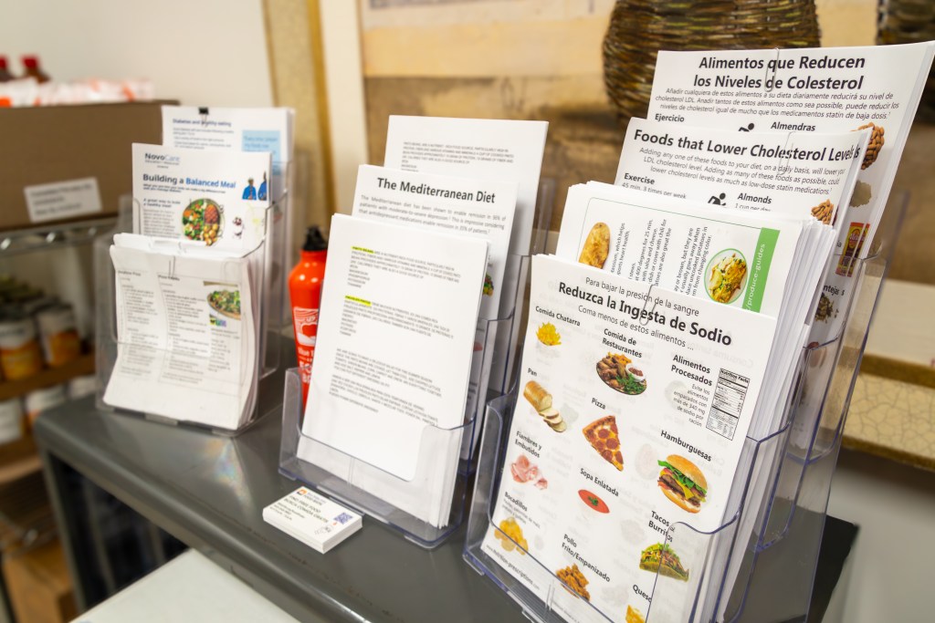 A small table in an office with a stack of business cards and a variety of pamphlets on display that explain nutrition information in English and Spanish.