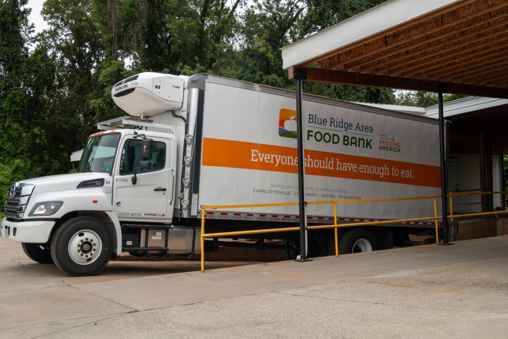 A large white delivery truck with "Blue Ridge Area Food Bank" written on the side sits next to a loading dock at a warehouse.