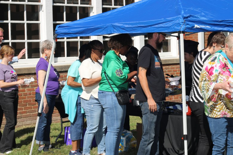 People line up for food under a canopy.