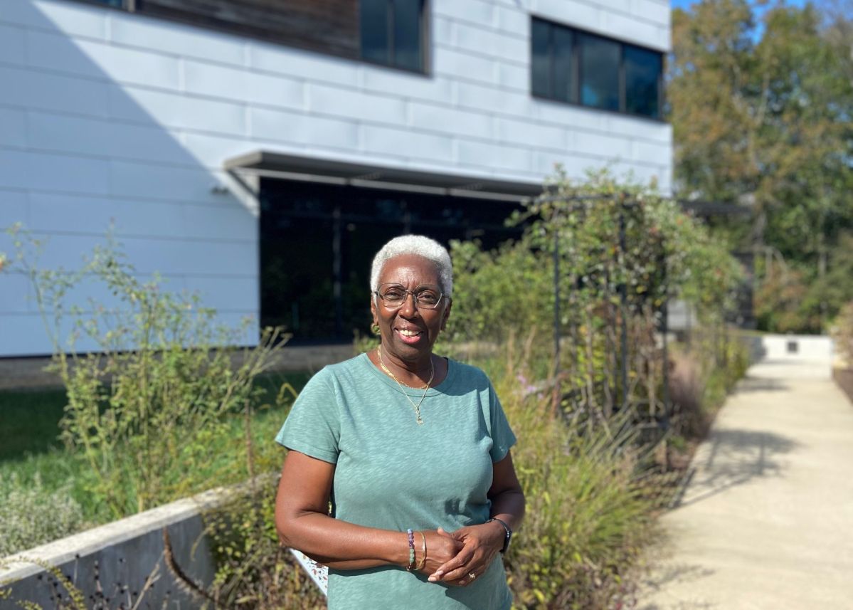 A woman stands in front of a building with modern architecture.