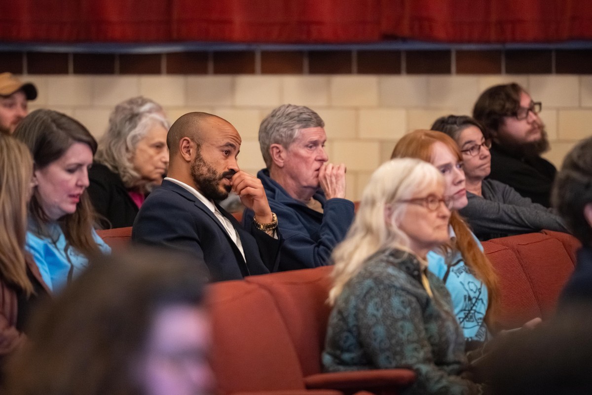 Around 10 individuals are sitting in an auditorium looking forward toward something off camera.