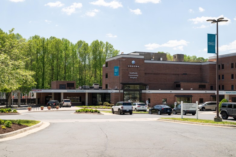 A large brick building and parking lot pictured on a sunny day, with large trees in the background. A large sign above the main entrance reads "Centra Southside Community Hospital."