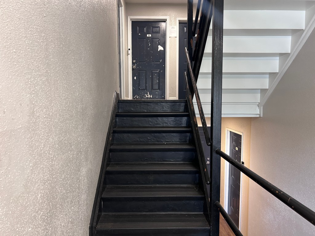 A stairwell connecting two storeys with doors. Paint on one door is chipped.