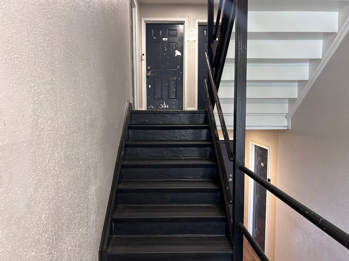 A stairwell connecting two storeys with doors. Paint on one door is chipped.